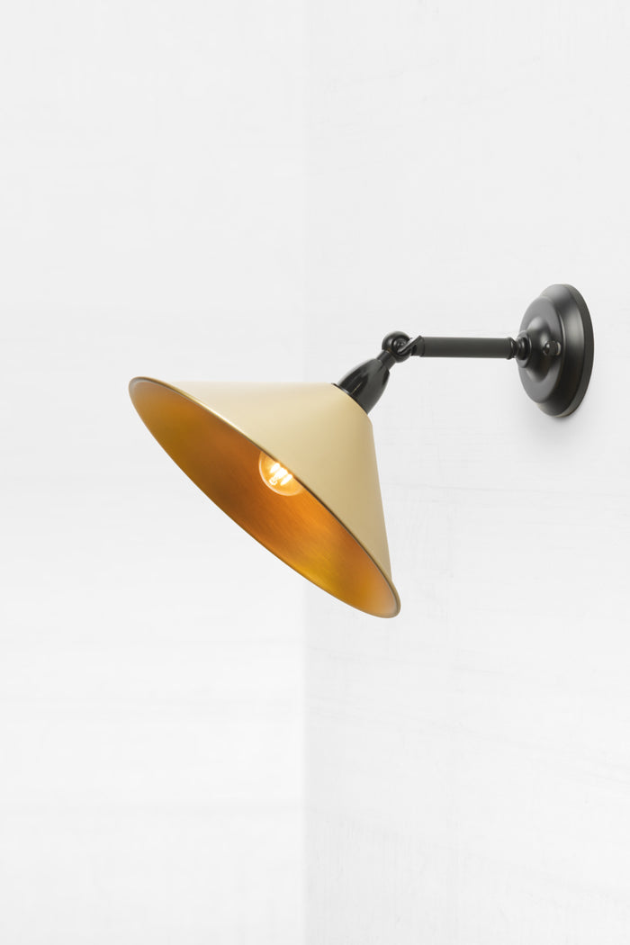 Small metal cone shade in bright brass on short straight arm, outdoor wall sconce with swivel lampholder.