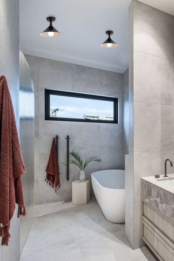Two blac cone shades on black flushmounts in a monochrome bathroom.