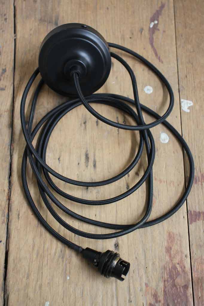 Black braided round pendant cord placed on a timber bench.