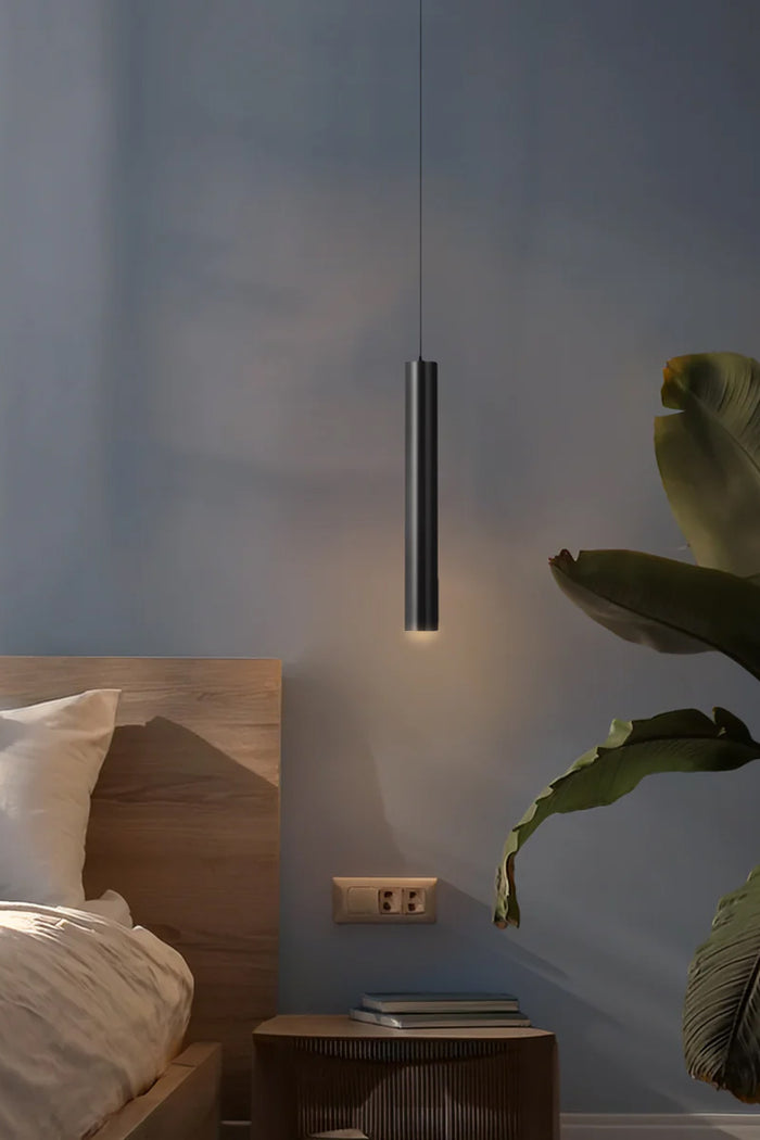 Gunmetal coloured LED slimline pendant light as a bedside light in a moody room with greenery.