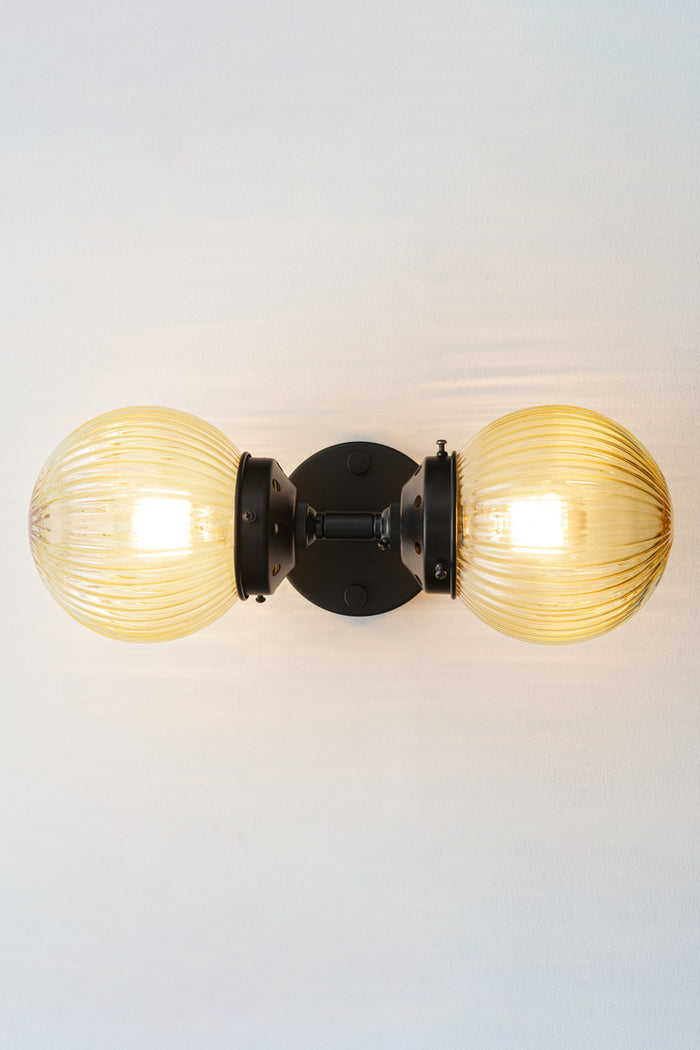 Dakota Reeded Glass Double Light Wall Sconce sitting horizontally with amber shades