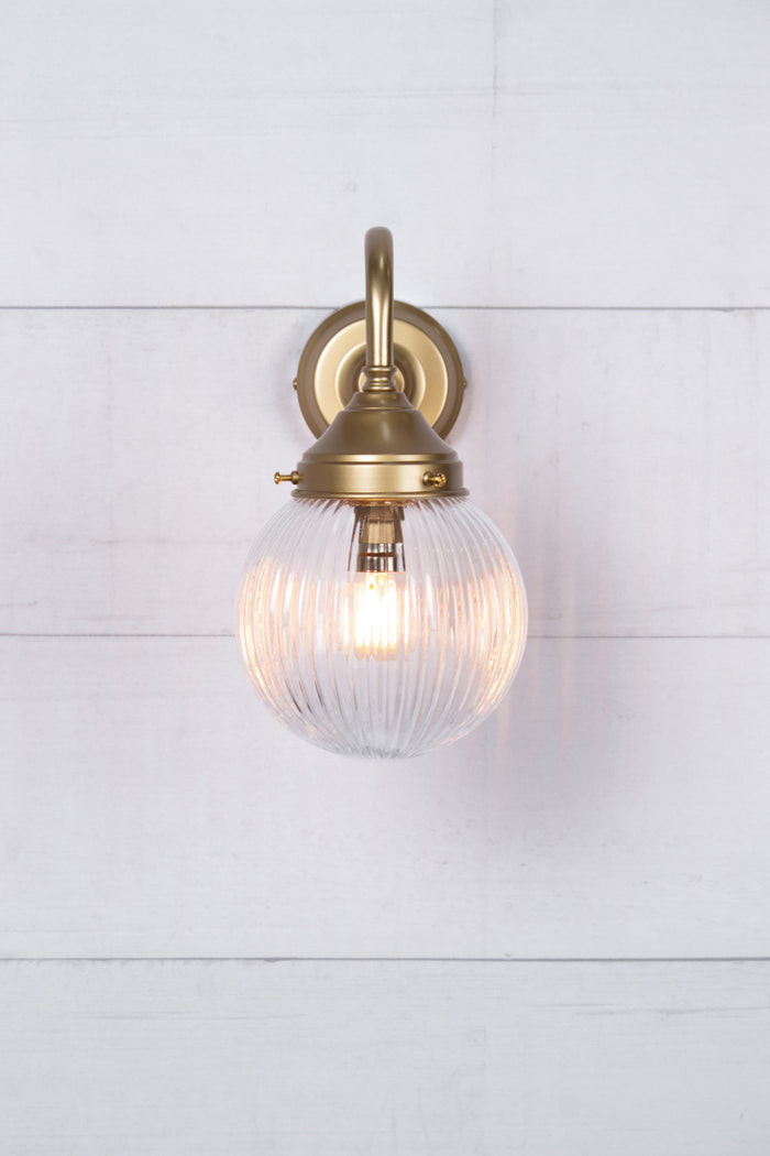 Front view of the exterior wall light with a gold/brass gooseneck arm and clear reeded shade.