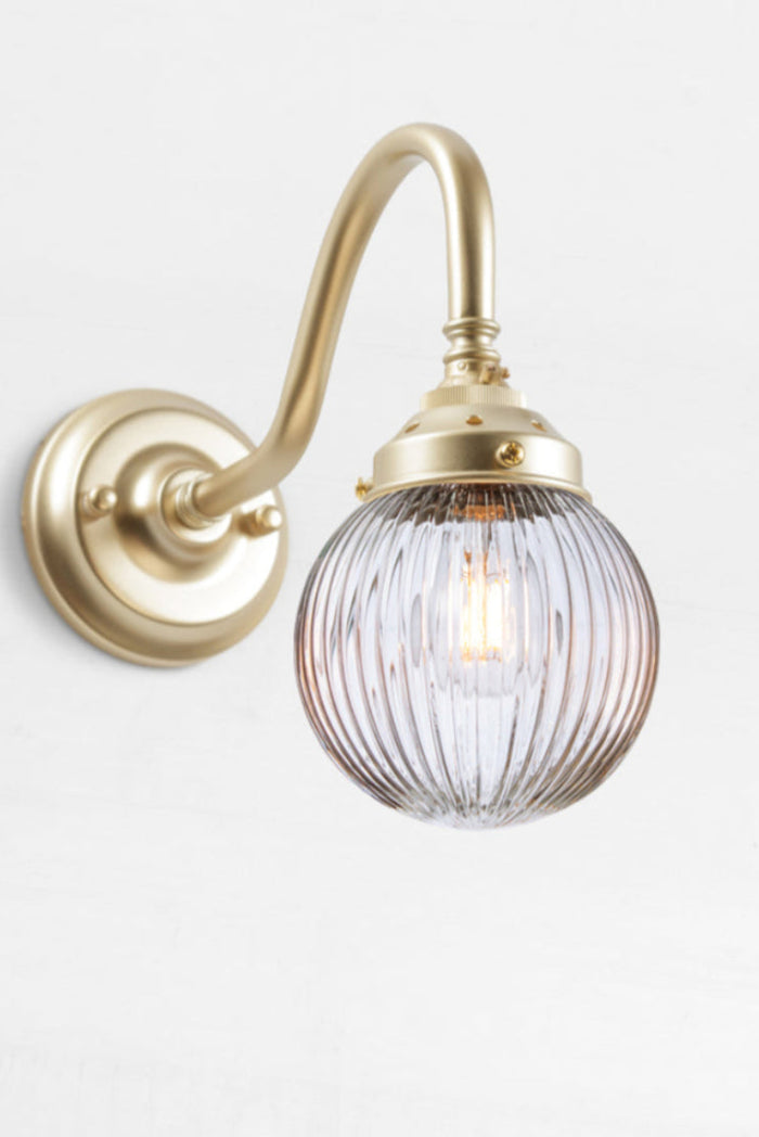Gold/brass gooseneck wall sconce with a clear reeded glass ball shade.
