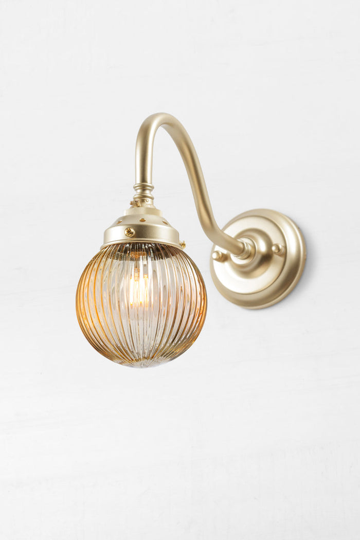 Gold/brass gooseneck wall sconce with an amber reeded glass ball shade.