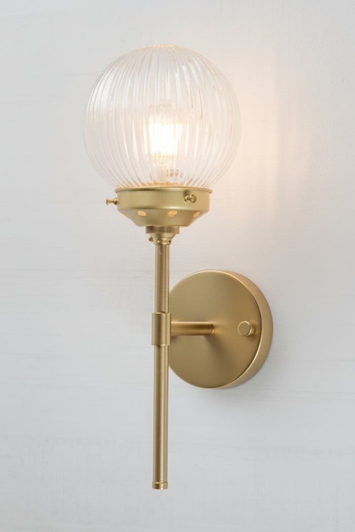 Gold/brass stem wall sconce paired with a clear reeded glass ball shade.