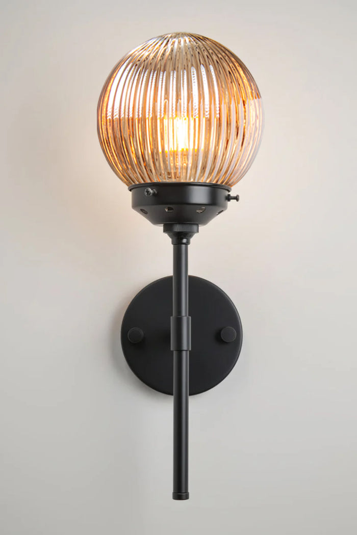 Reeded glass ball shade in dark amber with a black stem wall ssconce