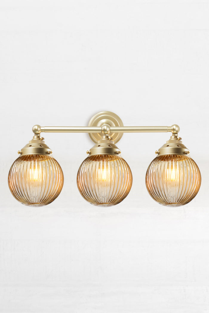 Gold/Brass three lampholder wall sconce paired with three amber reeded glass ball shades.