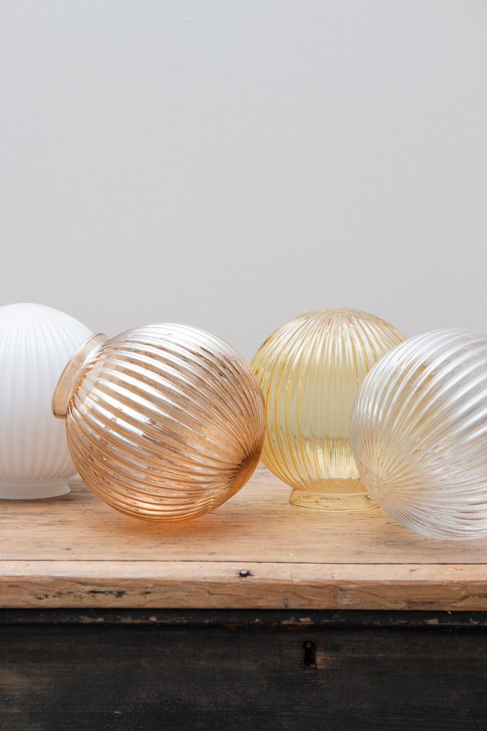 Glass ball shades in dark amber, opal, clear and amber finishes with reeded detailing on a timber bench.