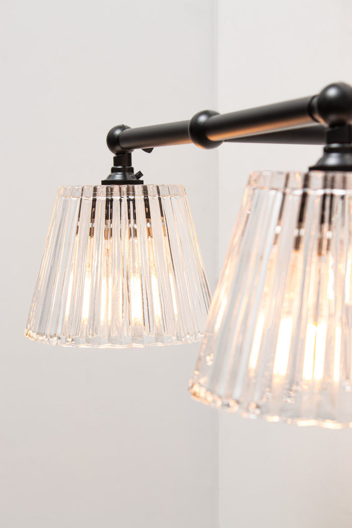 Close-up of black Davis Double Swivel Arm Wall Light with textured clear glass shades