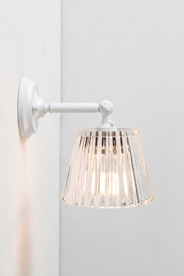 Side view of the white armed Davis Glass Swivel Arm Wall Light, illuminated against a light wall
