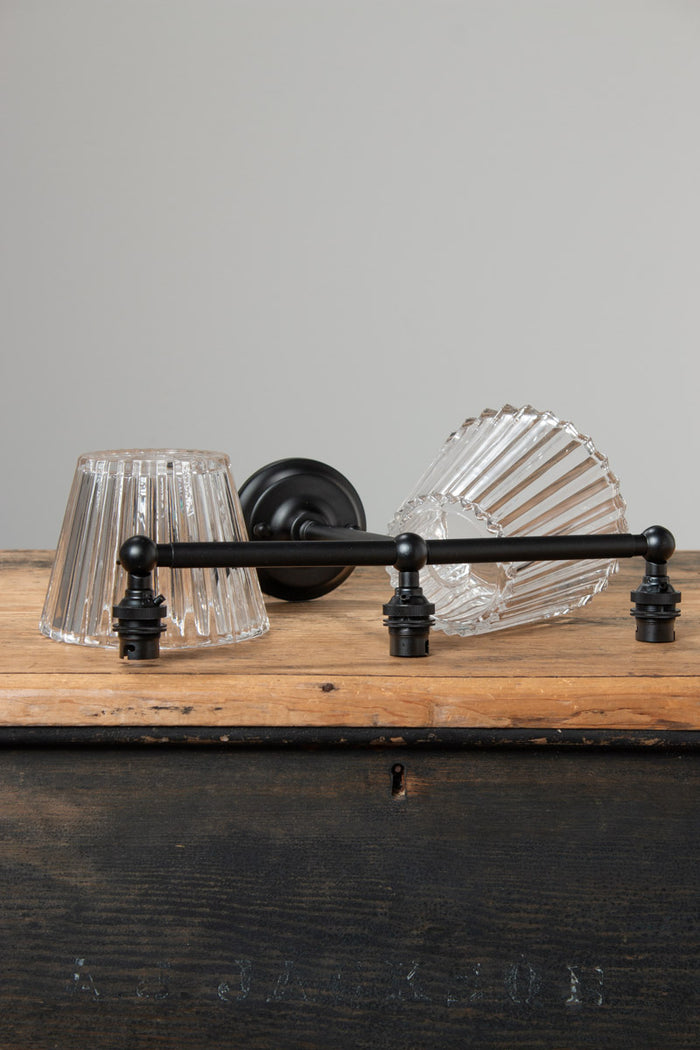 Davis Glass Triple Swivel Arm Wall Light in black with three clear fluted glass shades on timber surface