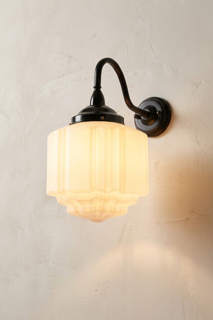 Wall-mounted light fixture with a opal deco lampshade on a light gray wall