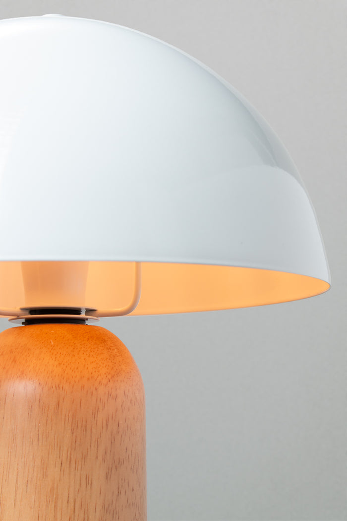 Close up of the table lamp with a white metal dome shade and rounded wood base with a natural finish.