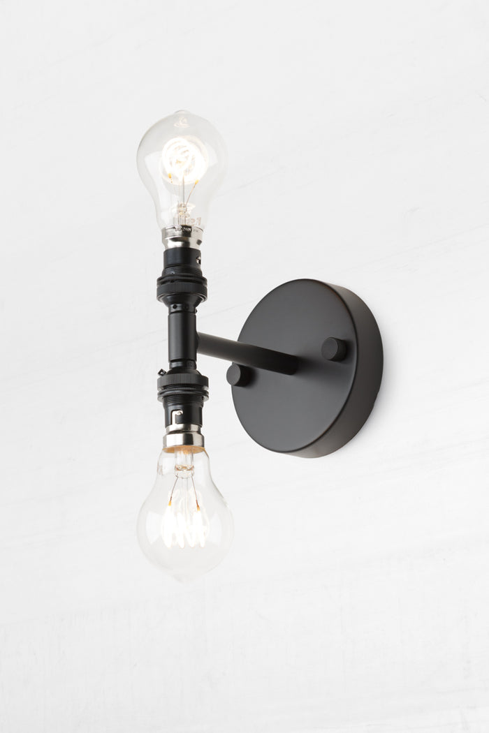 Double Wall Sconce Light in black, paired with two A60 clear bulbs.