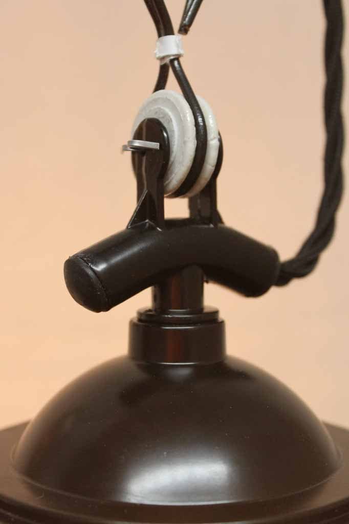 It features a tear drop shaped glass shade to house its light bulb which is encased by a black metal cage. its chain suspension with protruding twisted cord oozes charm and is a