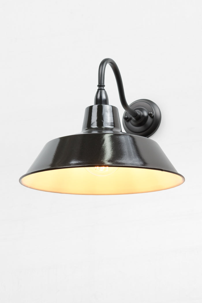 Outdoor wall sconce with a black gooseneck arm and large steel shade.