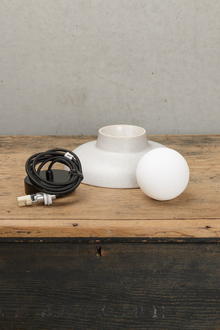 Uninstalled large ceramic pendant light with black cord and ceiling rose and an opal glass ball shade.
