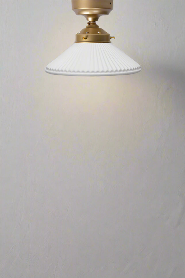 White ceramic pleated shade on a goldbrass batten holder and gallery.