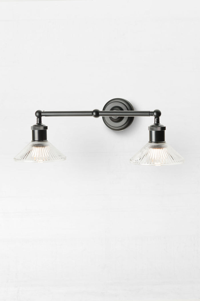 Side view of the black double swivel wall sconce with two clear reeded glass shades.