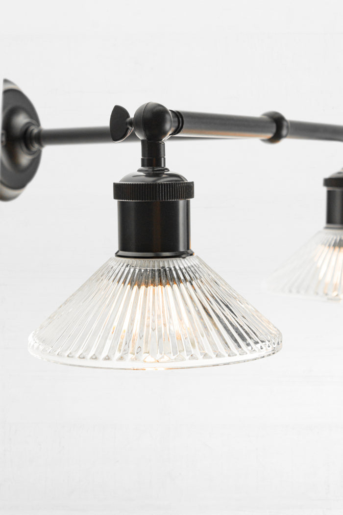 Close up of the Black double swivel wall sconce with two clear reeded glass shades.