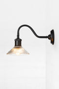 Side view of the clear pleate glass shade on the black gooseneck outdoor wall sconce.