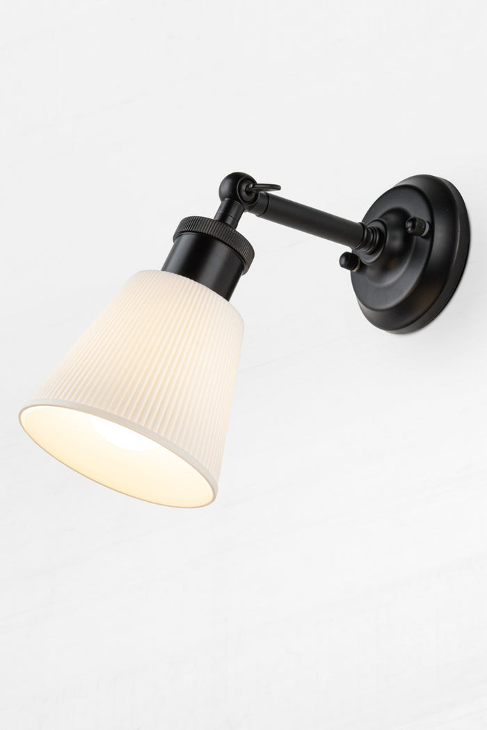 Small ceramic shade on short swivel straight arm wall sconce.