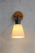 Close up of a small cermaic shade with a black tiltable arm with a wooden wall mount
