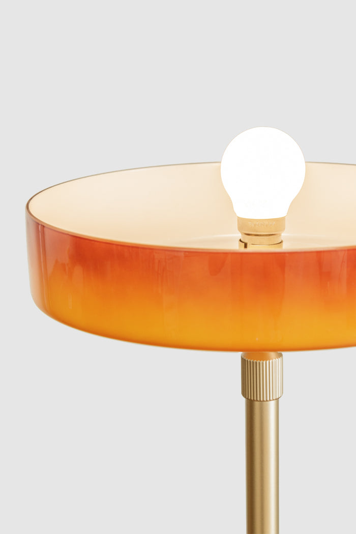 Detailed view of the amber shade with exposed globe and brass-toned fitting