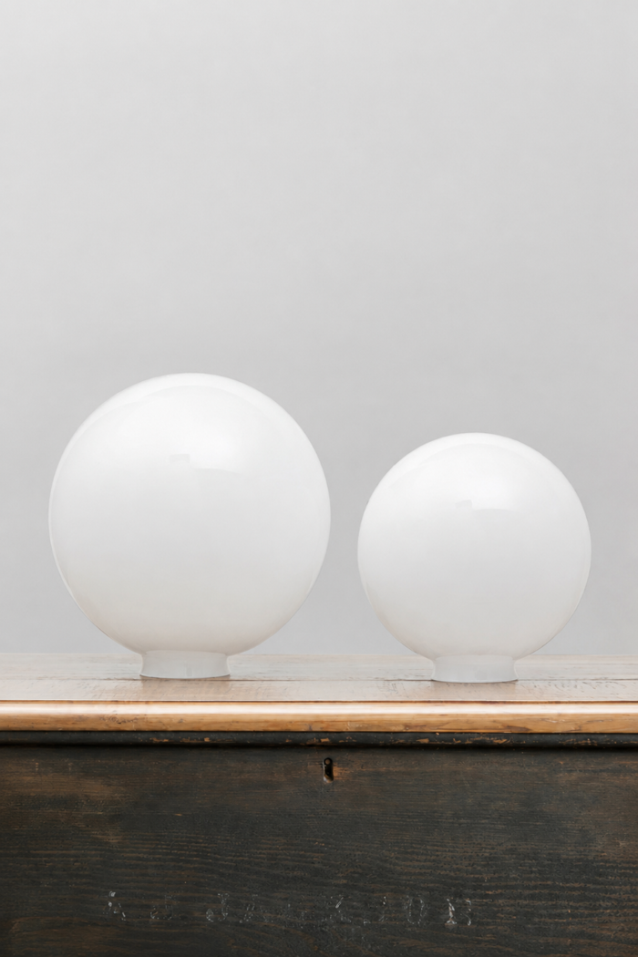 Medium and large opal glass ball shades, placed on a timber bench.