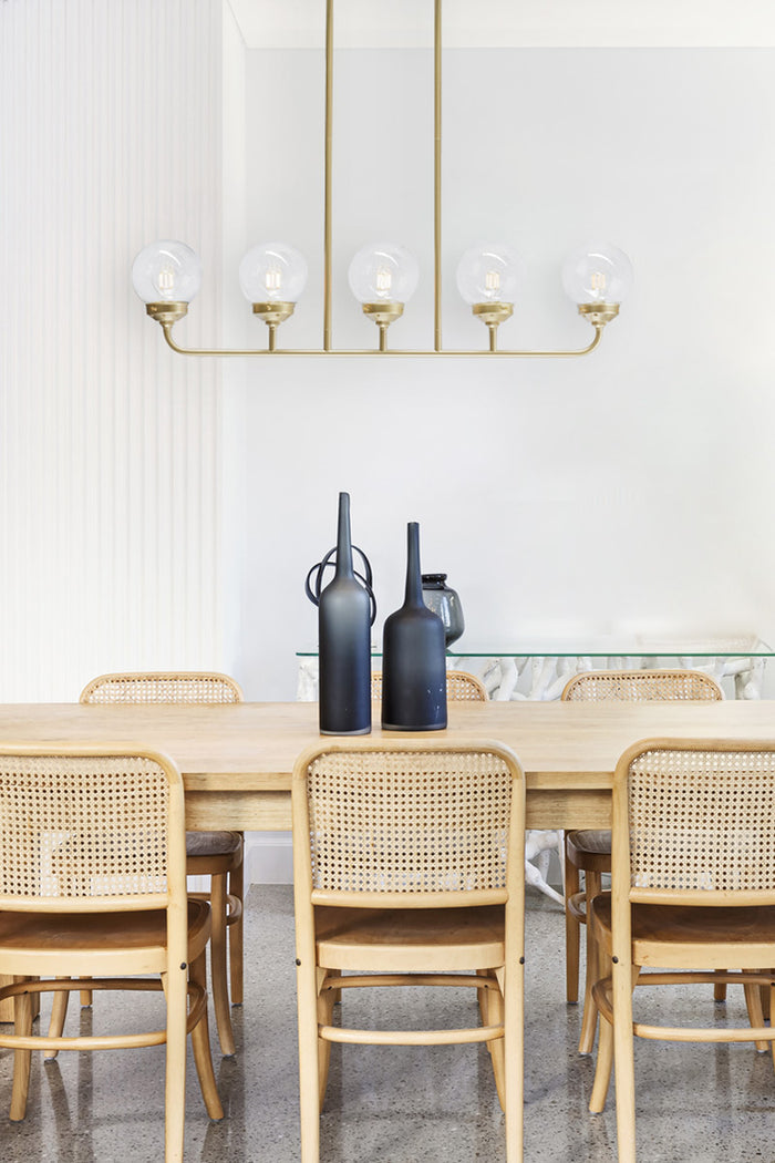 Gold/brass 5 lamp linear chandelier with clear glass ball shades.
