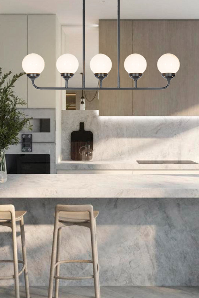 Five light glass ball opal shades on the black linear chandelier in a kitchen.