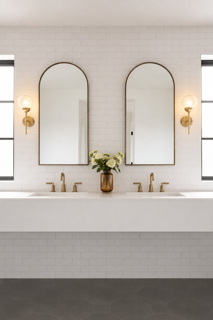 Two gold brass steel stem wall sconces paired with an opal glass ball shades, either side of double mirrors in a powderoom.