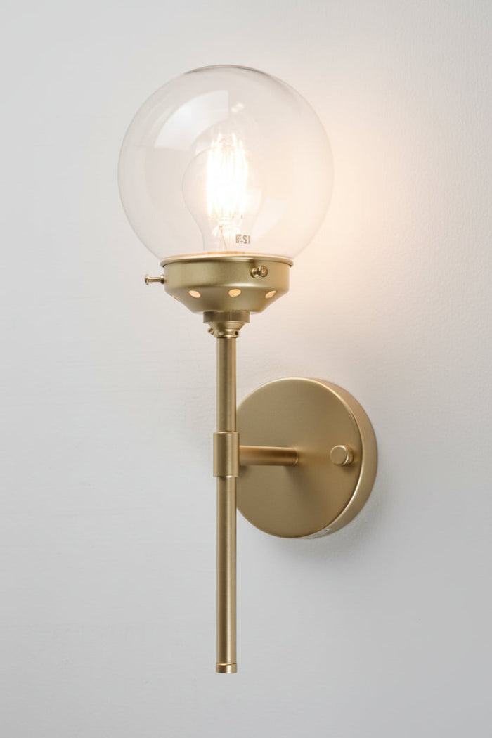 Gold/brass steel stem wall sconce paired with an clear glass ball shade
