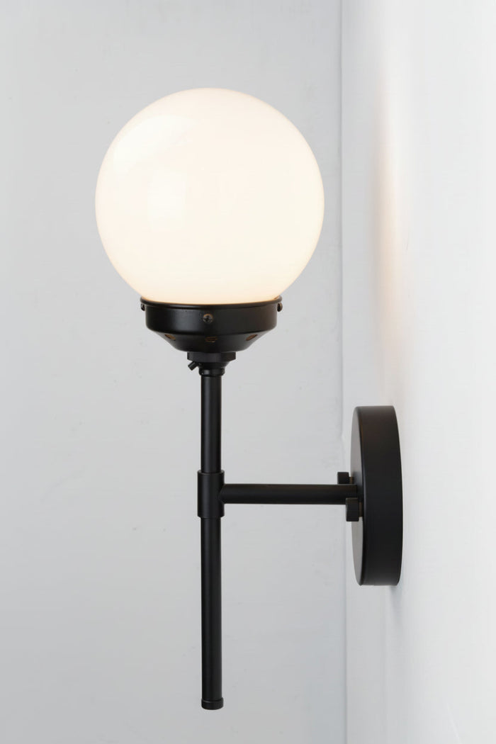 Wall-mounted light fixture with a round opal glass shade on a white wall.