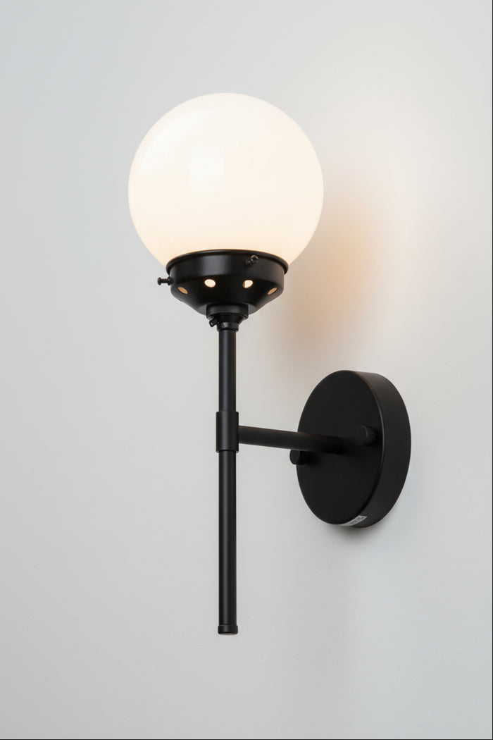 Black steel stem wall sconce paired with an opal glass ball shade