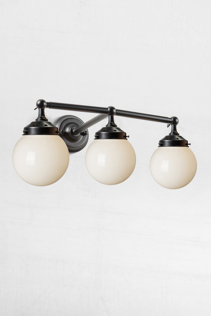 Under view of the triple lamp swivel arm wall sconce in black, with opal glass ball shades.