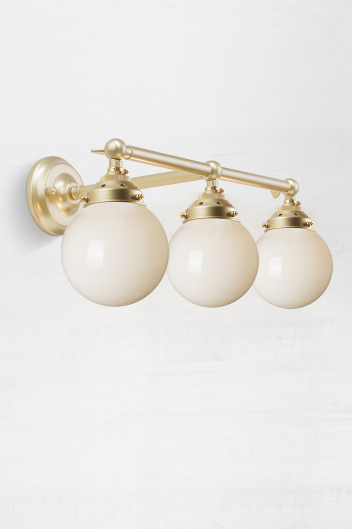 Under view of the triple lamp swivel arm wall sconce in gold/brass, with opal glass ball shades.