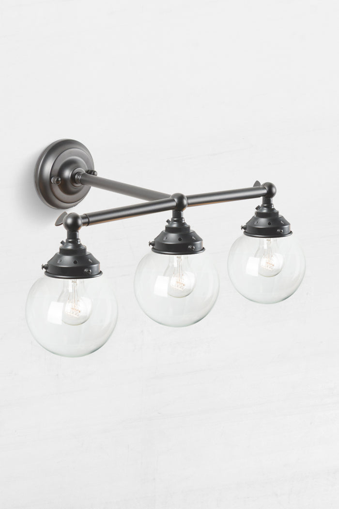 High view of the triple lamp swivel arm wall sconce in black, with clear glass ball shades.