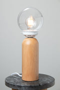 Clear glass ball shade, white gallery paired with a wood table lamp base on a marble look ride able.