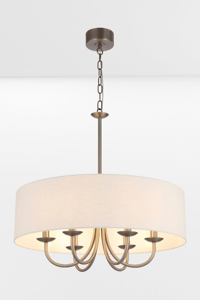 Nickel framed chandelier with four lights and a white fabric drum shade, pictured with lights on.