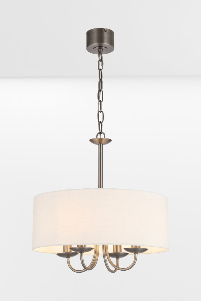 Nickel framed chandelier with four lights and a white fabric drum shade, pictured with lights on.