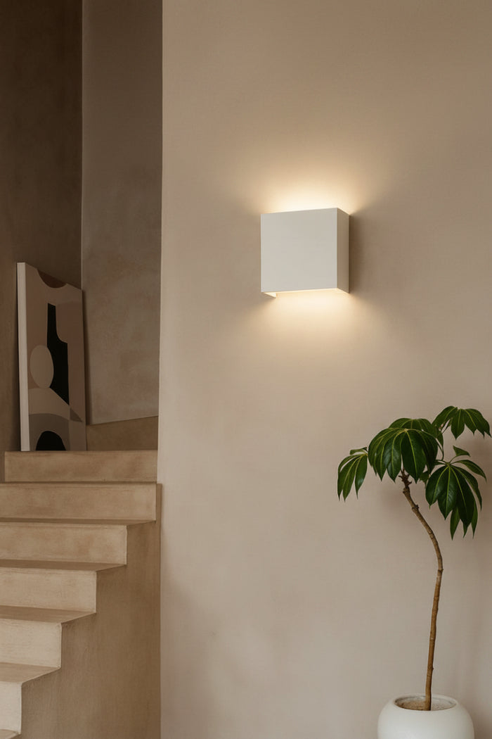 Griffs Plaster Wall Sconce installed on a textured feature wall, showcasing the white paintable plaster finish with soft up and down lighting.