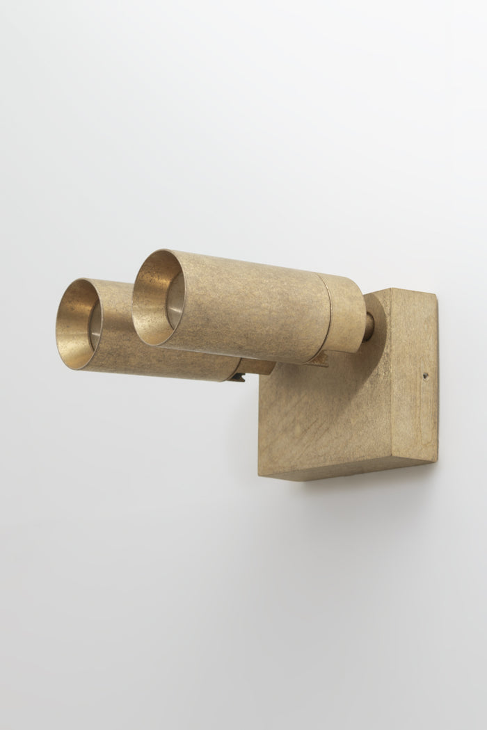 Brass wall-mounted light fixture with adjustable heads on a white outdoor wall