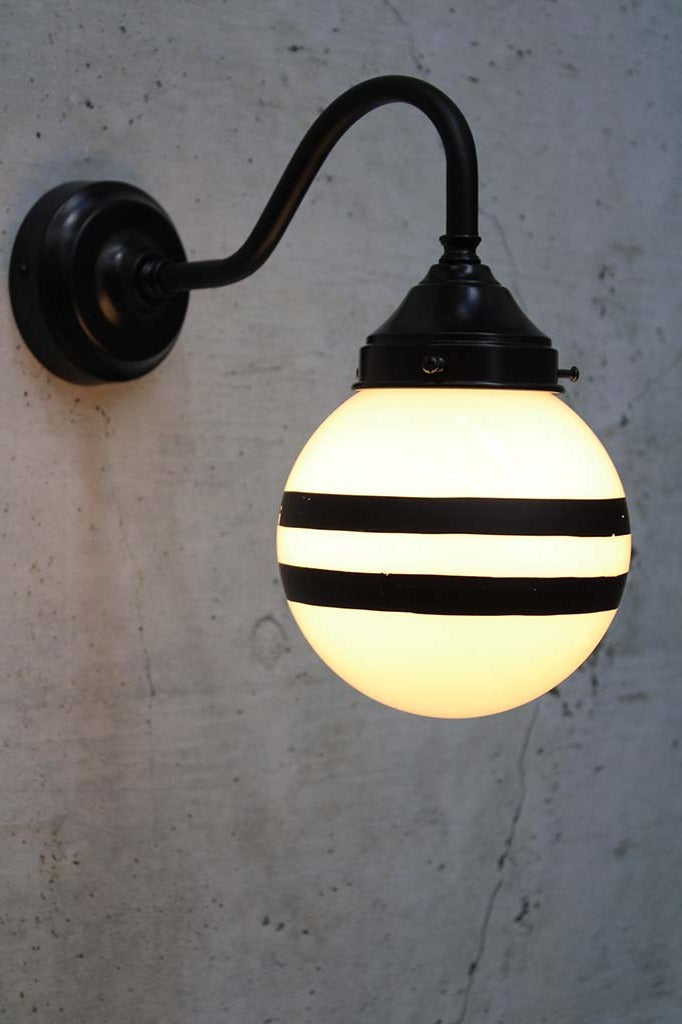 Hand painted opal glass ball pendant light with two stripes on black steel sconce.