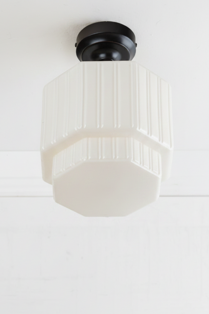 Opal glass shade with step silluette and unique fluted side detailing, paired with a black batten.