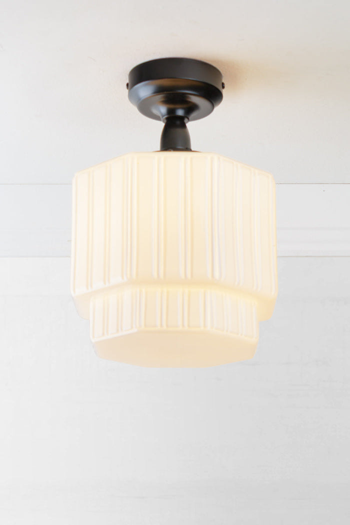 Opal glass shade with step silluette and unique fluted detailing, paired with a black batten holder and gallery.