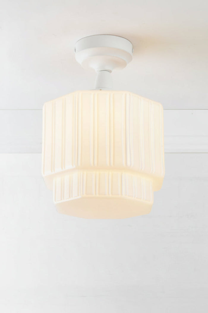 Opal glass shade with step silluette and unique fluted detailing, paired with a white batten holder and gallery.