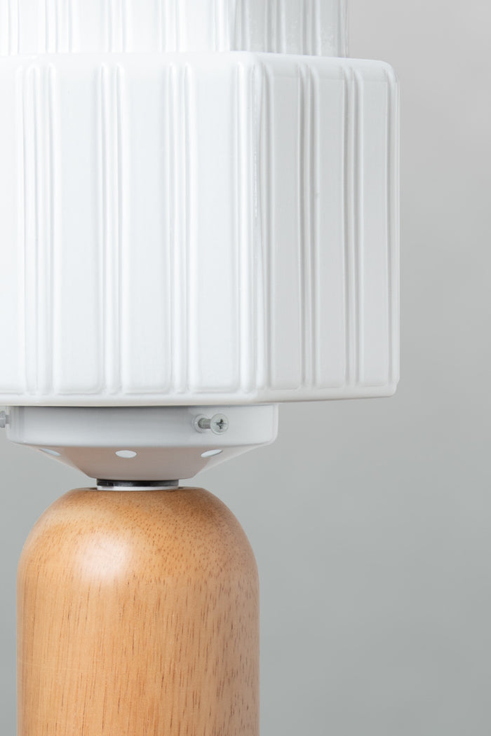 Close up of Harcourt opal glass shade with fluted stepped detailing on natural wood table lamp base.