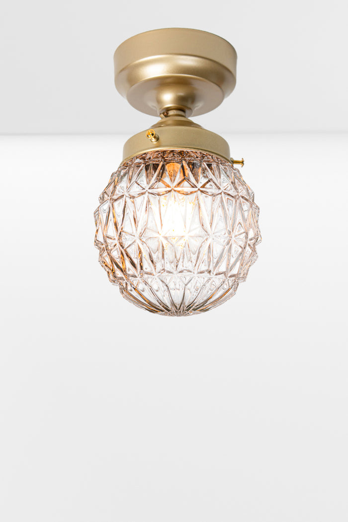 Clear glass ball shade with geometric vintage deatiling, on a gold/brass batten holder.
