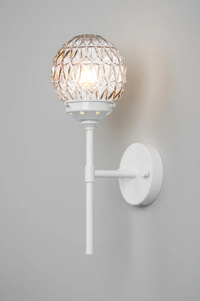 Clear glass ball shades with diamon-cut detailing paired with a white steel stem wall sconce.